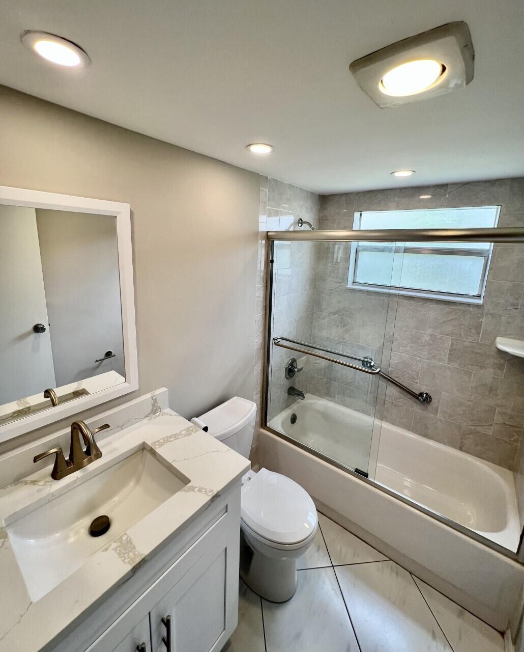 20 Saxony A, Unit A Delray Beach, FL 33446 - Photo 10 of 50 a bathroom with a sink toilet vanity and shower