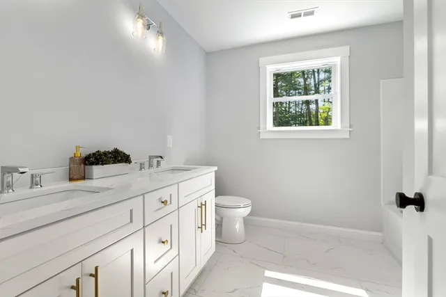 a bathroom with a granite countertop sink mirror vanity and toilet