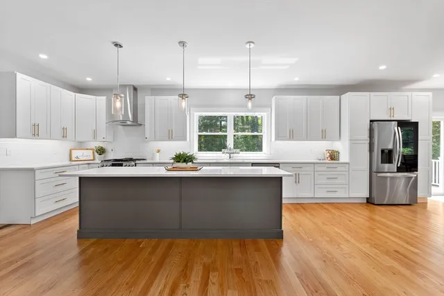 a kitchen with stainless steel appliances granite countertop a stove a sink and white cabinets with wooden floors