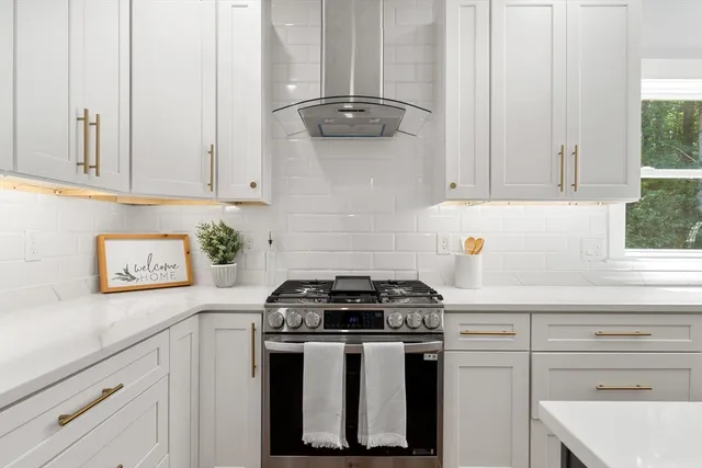 a kitchen with granite countertop white cabinets and a stove