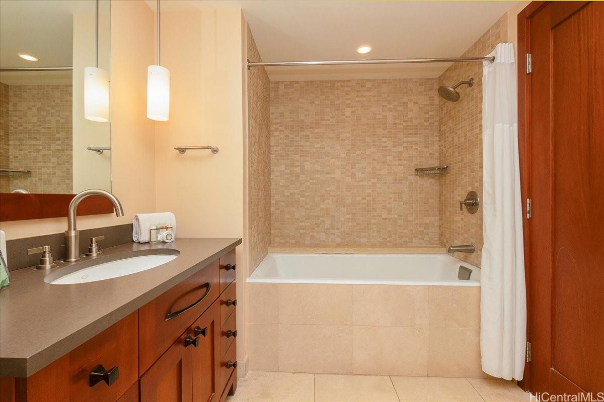 92-104 Waialii Place, Unit O422 Kapolei, HI 96707 - Photo 14 of 25 a bathroom with a granite countertop sink a mirror a shower and a bathtub