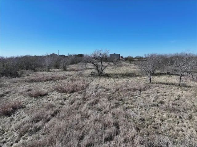 a view of a dry field with mountains in the background