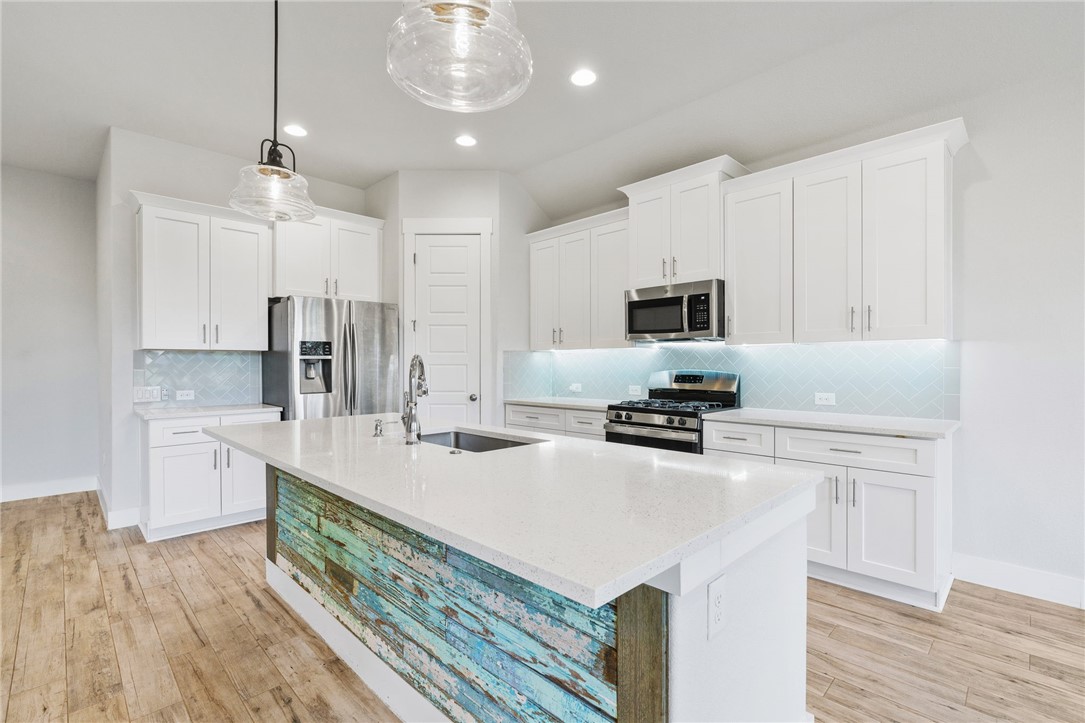 941 Del Raphael Drive Leander, TX 78641 - Photo 10 of 33 Quartz countertops contrast beautifully with the detailed herringbone tile backsplash