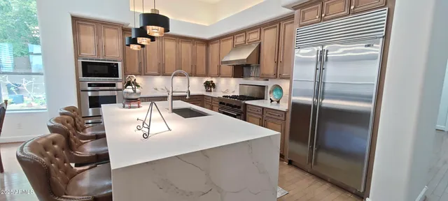 a kitchen with stainless steel appliances granite countertop a sink a stove and a refrigerator
