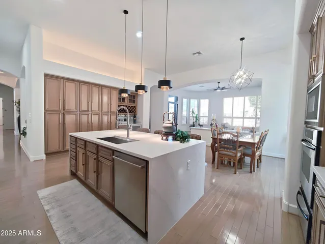 a kitchen with stainless steel appliances granite countertop a refrigerator a sink a stove and chairs with wooden floor