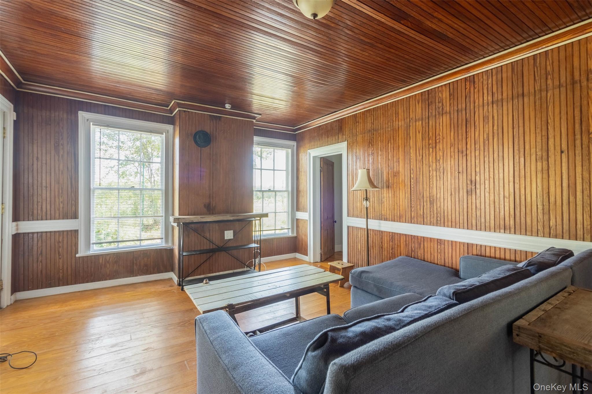 19450 Main Road Mattituck, NY 11952 - Photo 7 of 16 Living room featuring wood-type flooring, crown molding, and wooden walls