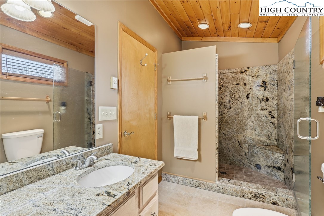 112 North Pinnacle Ridge Road Beech Mountain, NC 28604 - Photo 15 of 40 a bathroom with a granite countertop shower a sink and a mirror