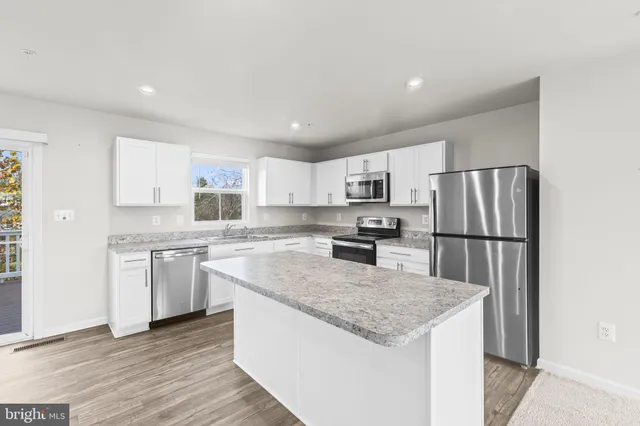 a kitchen with stainless steel appliances granite countertop a refrigerator a sink a stove a microwave and island