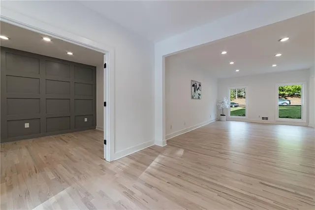 an empty room with wooden floor and natural light