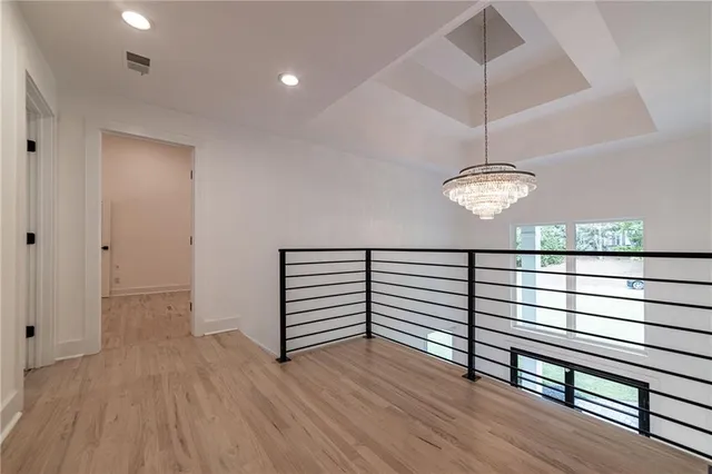 a view of an empty room with wooden floor and windows