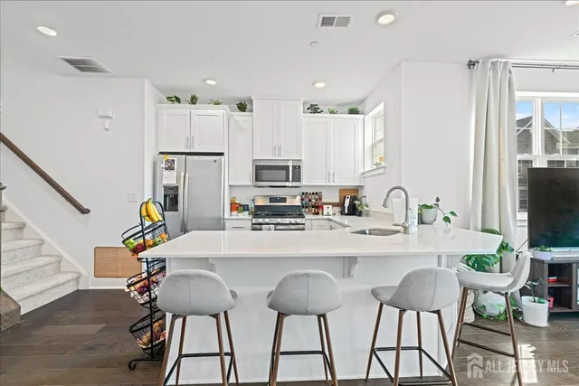 a kitchen with stainless steel appliances kitchen island a table chairs refrigerator and sink