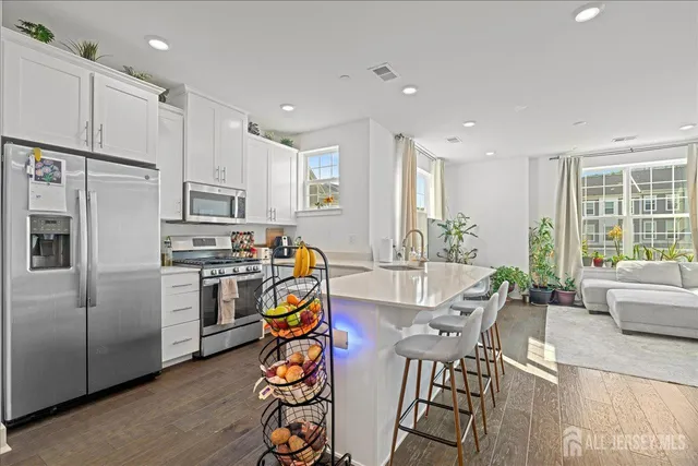 a view of kitchen with stainless steel appliances refrigerator stove dining table and chairs