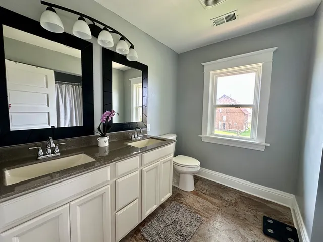 a bathroom with a granite countertop sink toilet and mirror