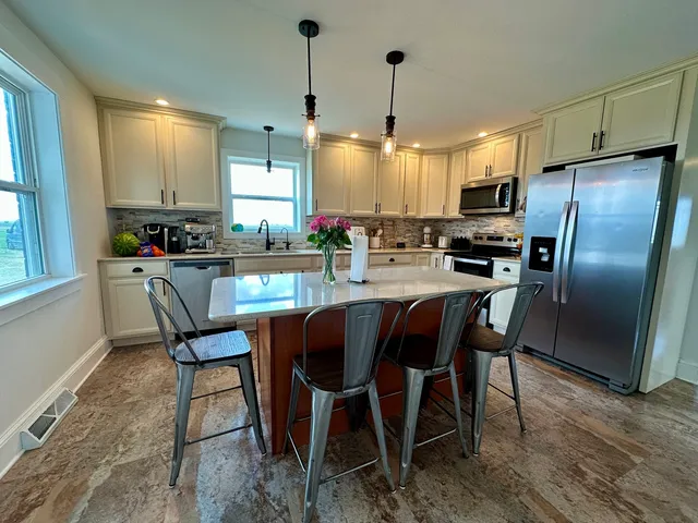 a kitchen with stainless steel appliances a dining table chairs stove refrigerator and microwave