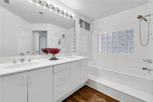 a bathroom with a double vanity sink mirror and bathtub