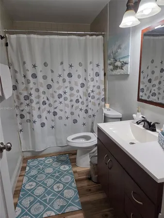 a bathroom with a sink a toilet and shower curtain