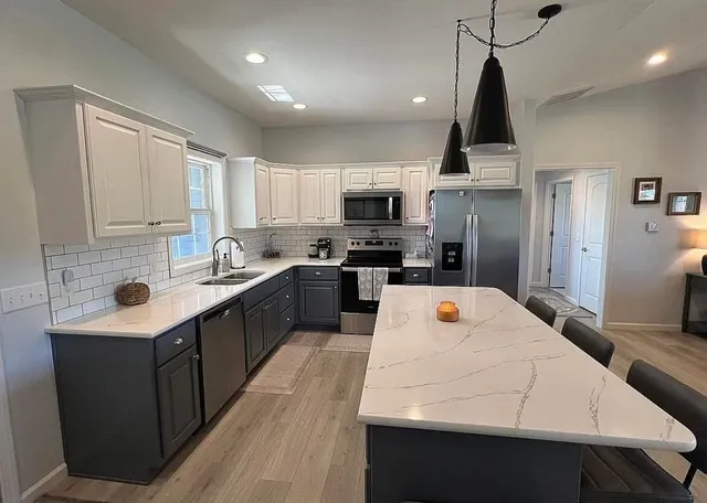 a large kitchen with a large counter top appliances a sink and cabinets