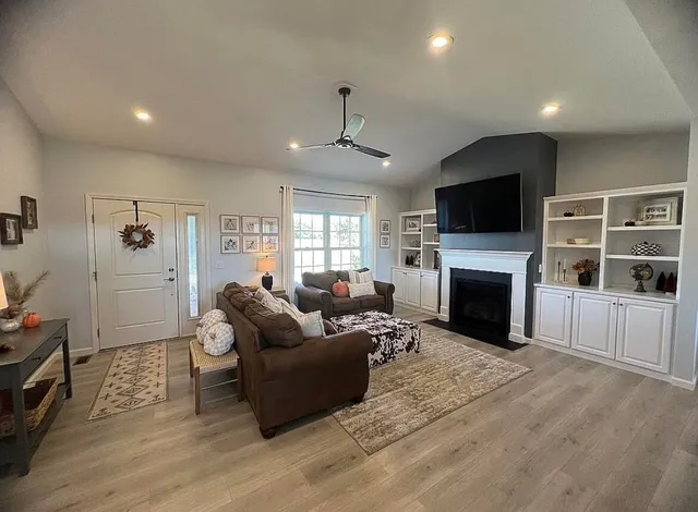 a living room with furniture a fireplace a flat screen tv and a window