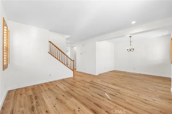 a view of an empty room with wooden floor and stairs