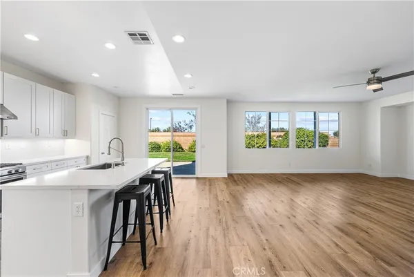 a kitchen with a sink white cabinets and wooden floor