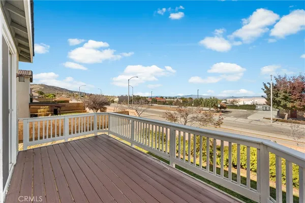 a view of an empty room with wooden floor and a ceiling fan