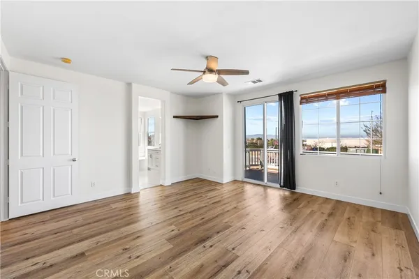 an empty room with wooden floor ceiling fan and window