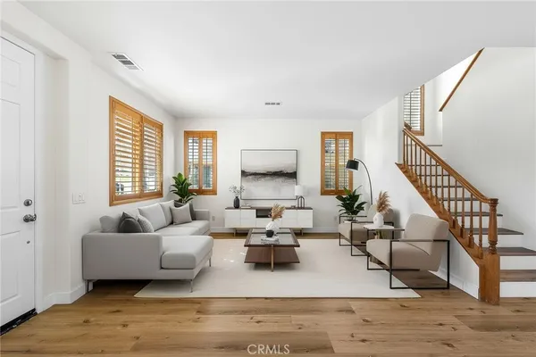 a living room with furniture a rug a dining table a window and a potted plant