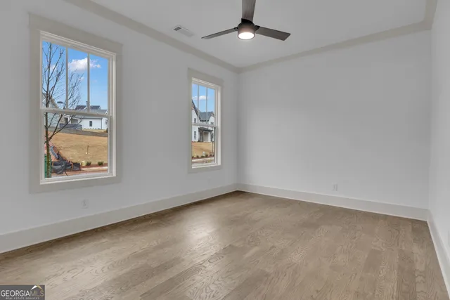 an empty room with windows and chandelier fan
