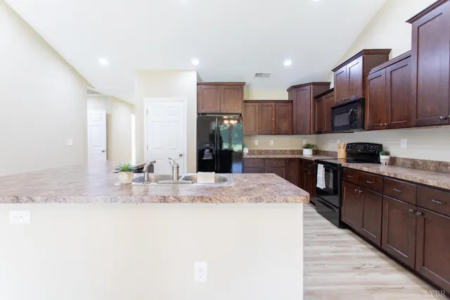 a kitchen with stainless steel appliances granite countertop a sink refrigerator and cabinets