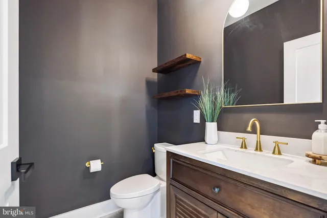 a bathroom with a granite countertop toilet sink and mirror