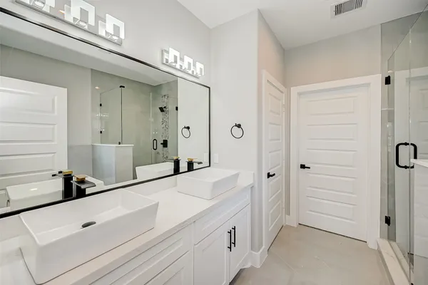 a bathroom with a double vanity sink a mirror and a shower