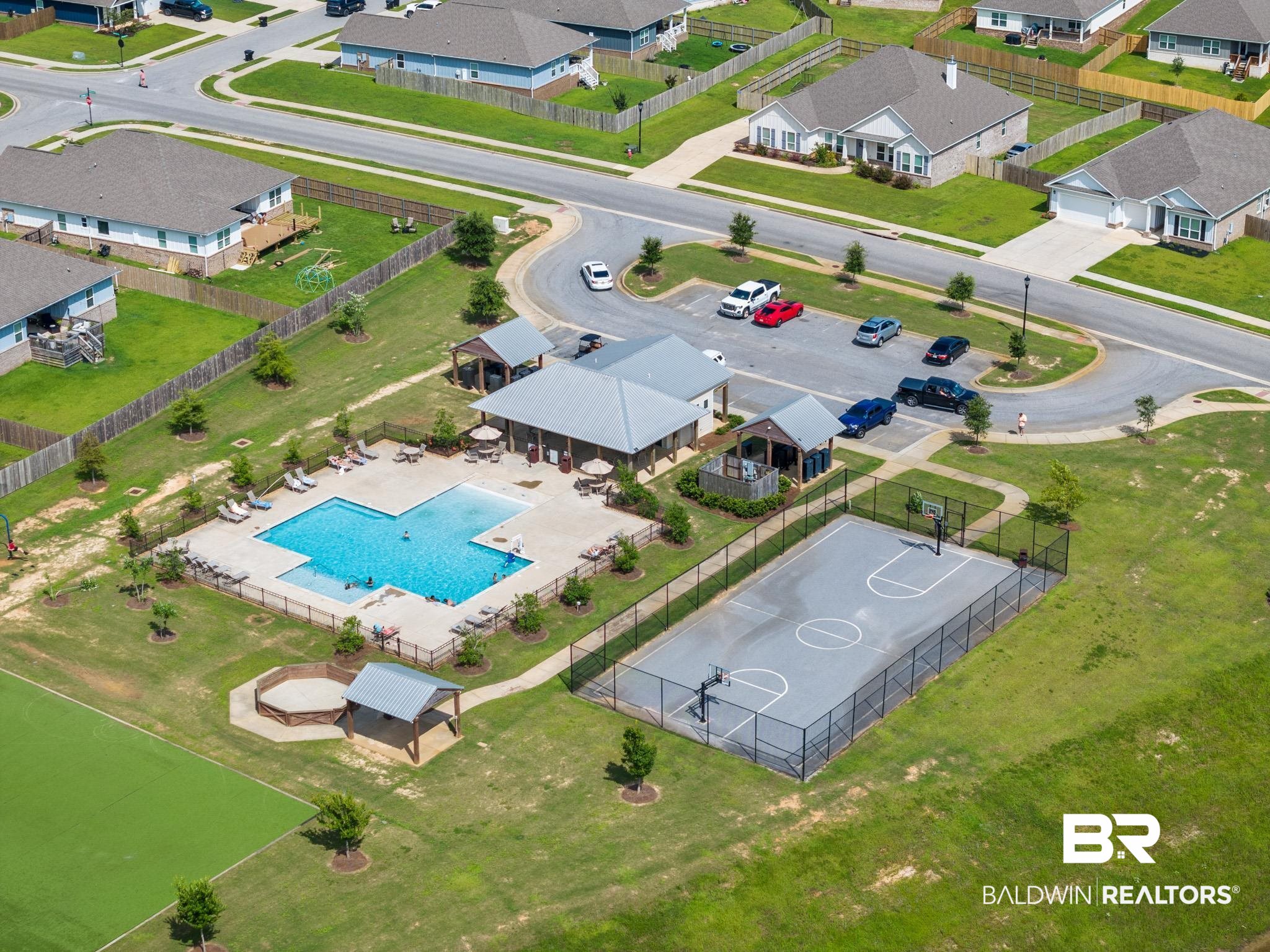 32125 Lyon Road Daphne, AL 36527 - Photo 45 of 70 Community recreation area featuring a large swimming pool with surrounding lounge space, a fenced basketball court, and a covered outdoor stage