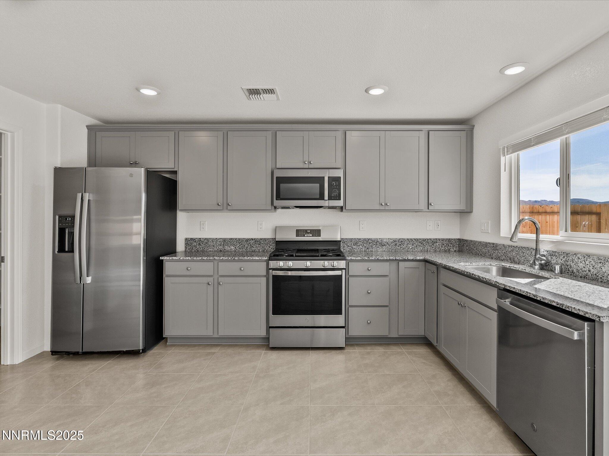 8838 Finnsech Drive Reno, NV 89506 - Photo 13 of 44 a kitchen with granite countertop a refrigerator and a stove top oven