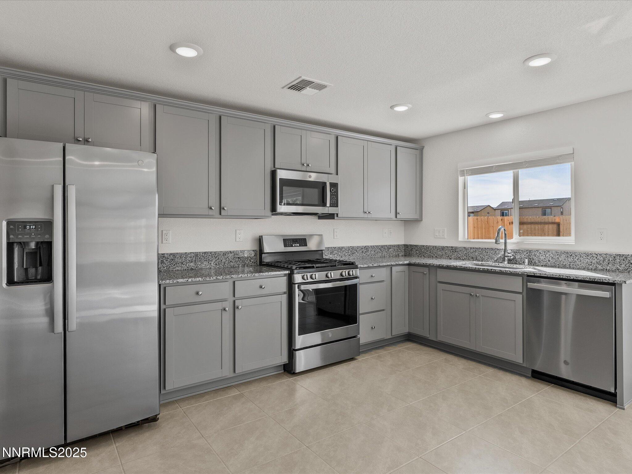 8838 Finnsech Drive Reno, NV 89506 - Photo 14 of 44 a kitchen with granite countertop white cabinets and stainless steel appliances