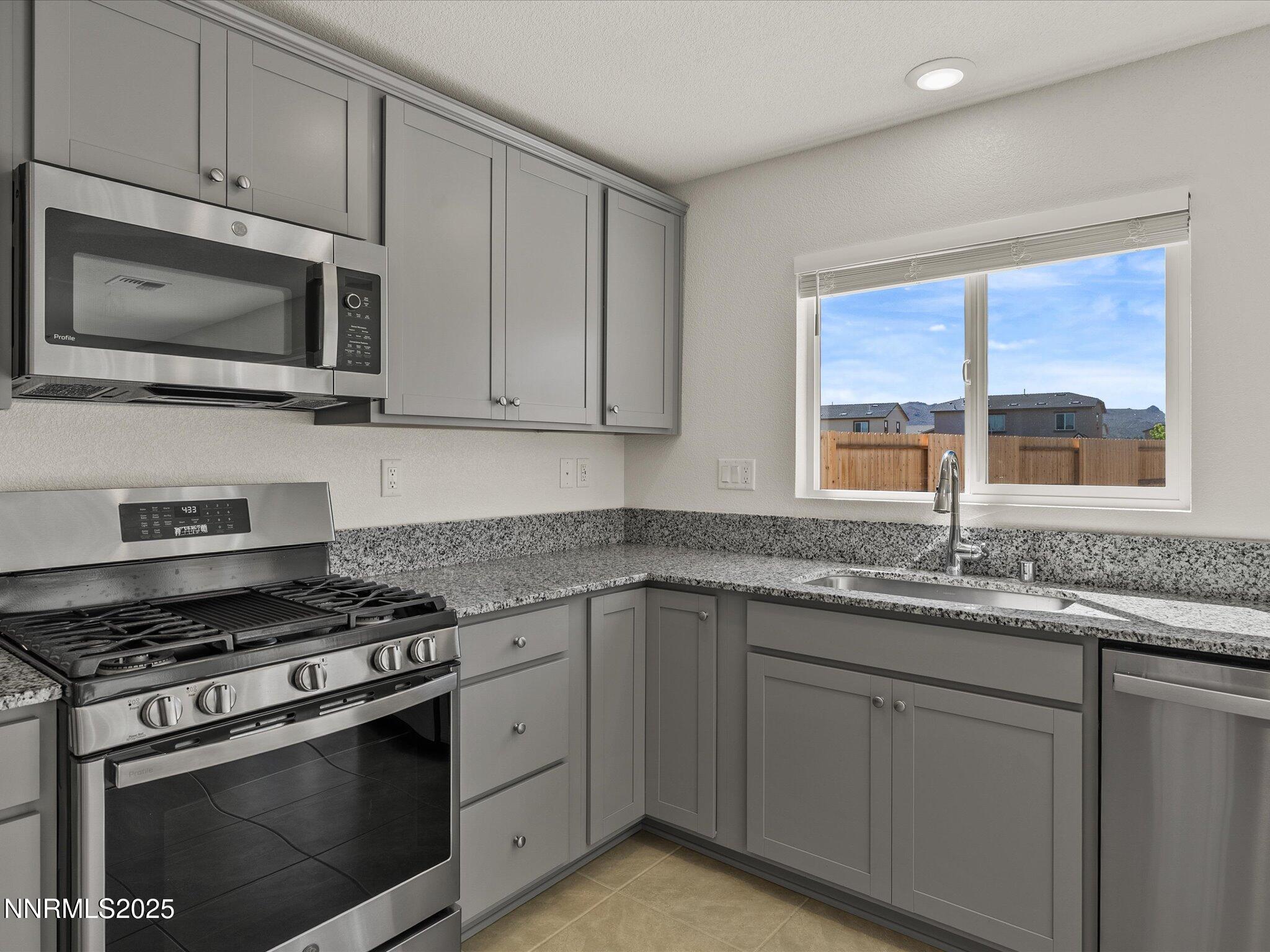 8838 Finnsech Drive Reno, NV 89506 - Photo 15 of 44 a kitchen with granite countertop a stove sink and microwave