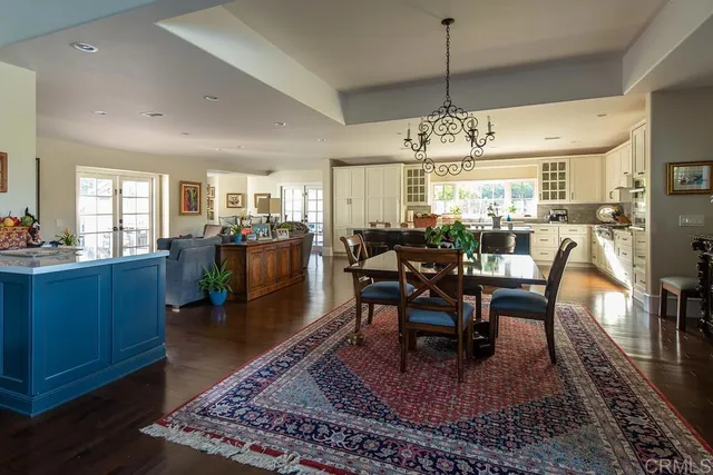 a view of a dining room and livingroom with furniture wooden floor a rug and a chandelier