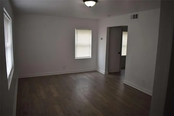 an empty room with wooden floor and windows