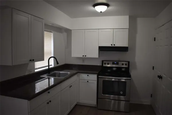 a kitchen with granite countertop white cabinets and black appliances