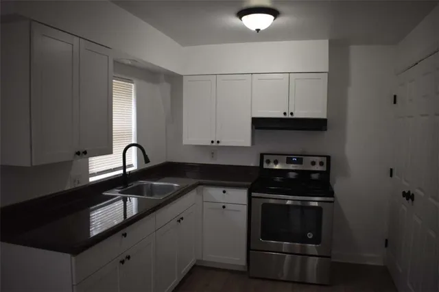 a kitchen with granite countertop white cabinets and black appliances