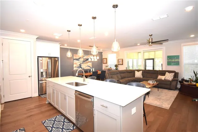 a living room with stainless steel appliances kitchen island granite countertop a sink and a refrigerator
