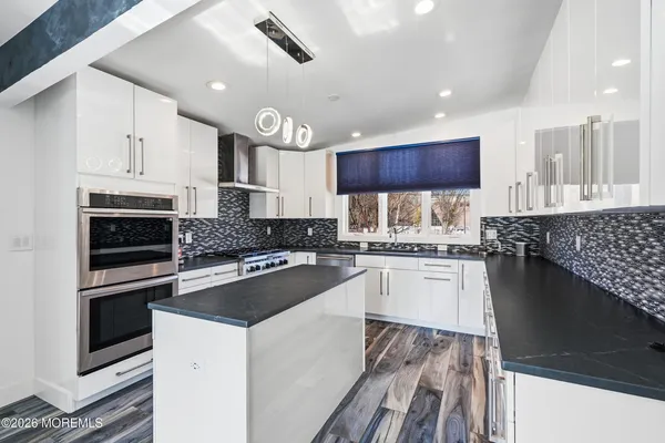 a kitchen with kitchen island granite countertop a sink cabinets and stainless steel appliances