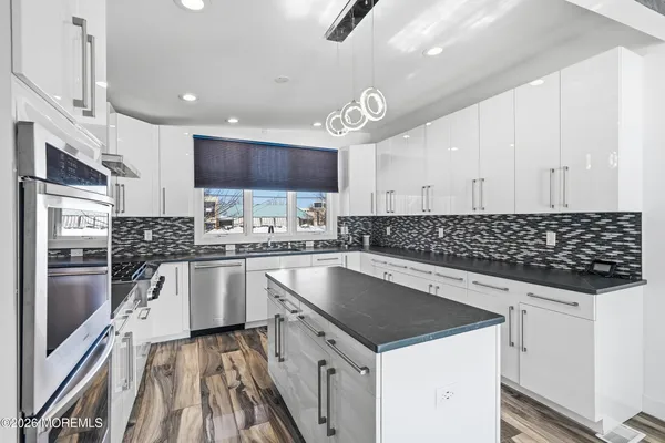 a kitchen with granite countertop stainless steel appliances a sink a stove top oven a counter space and cabinets