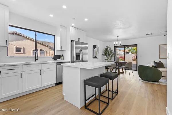 a kitchen with kitchen island white cabinets a refrigerator a oven a stove a dining table and chairs