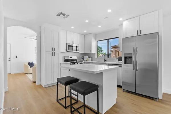 a kitchen with stainless steel appliances granite countertop a sink a stove a refrigerator cabinets and a window
