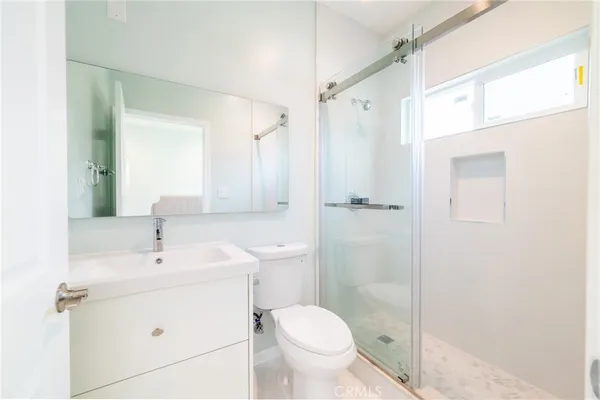 a bathroom with a shower sink vanity mirror and toilet