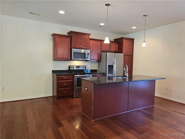 a kitchen with stainless steel appliances granite countertop a refrigerator a stove top oven a sink and dishwasher with wooden floor