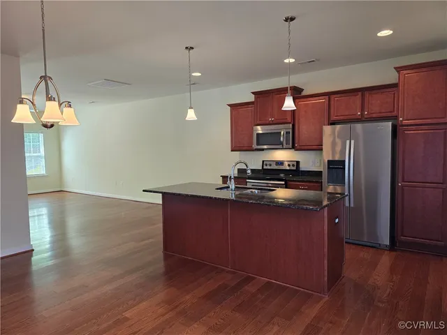 a kitchen with stainless steel appliances granite countertop a refrigerator a sink dishwasher a stove and a refrigerator