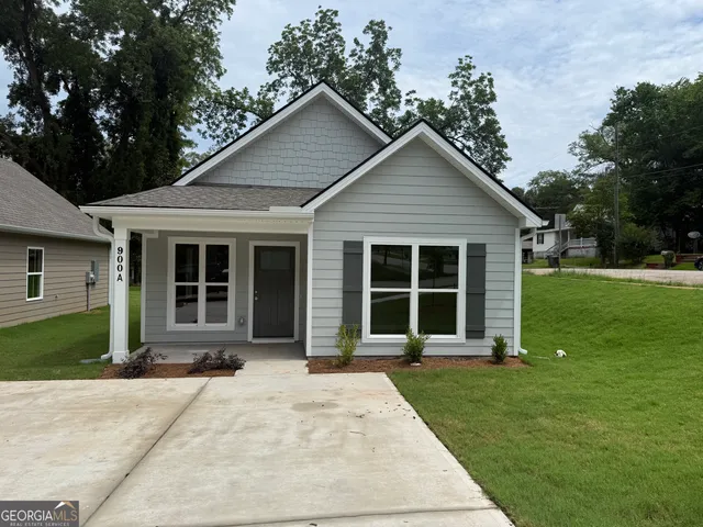 a view of a house with a yard plants and large tree