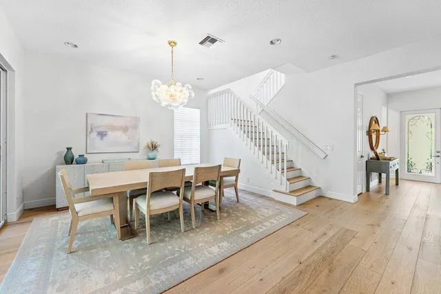 a dining room with wooden floor a chandelier a wooden table and chairs