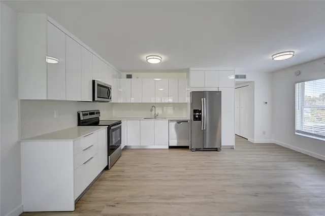 a kitchen with white cabinets and stainless steel appliances